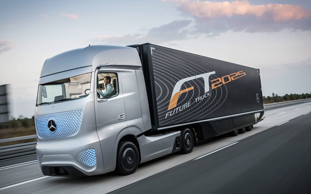 Futuristic looking truck with driver occupied on a laptop not steering vehicle