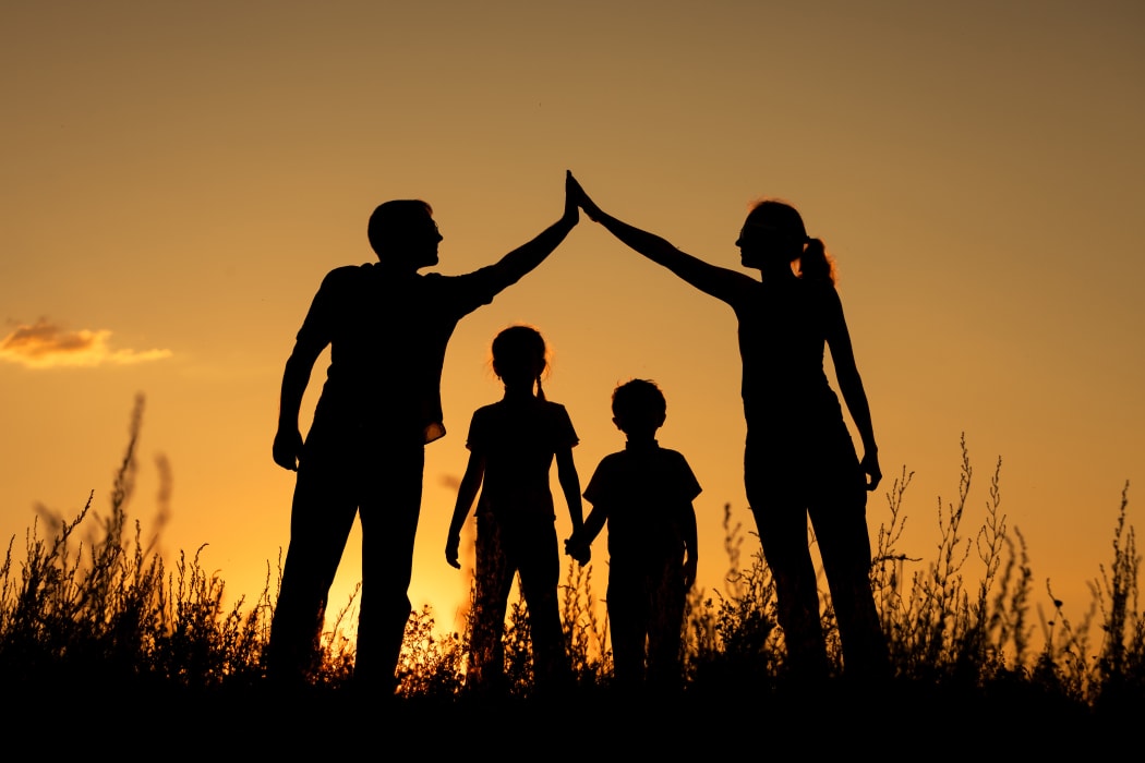 Happy family standing in the park at the sunset time.  Concept of friendly family.