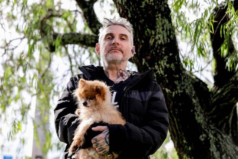 Author Dominic Hoey holding Pomeranian rescue dog, Chilli, in his arms as they stroll the streets of Grey Lynn, Auckland, where his new book, 1985 is set.