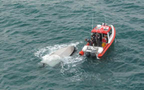 The Coastguard vessel next to the overturned boat.