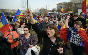 Supporters of presidential candidate Calin Georgescu demonstrate with flags ouside the Constitutional court in Bucharest on March 11, 2025. Romanian far-right politician Calin Georgescu on March 11, 2025 lost his appeal against a decision barring him from standing in the country's presidential election re-run, as hundreds gathered in his support outside the court. (Photo by Daniel MIHAILESCU / AFP)
