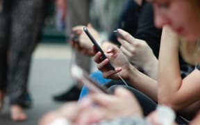 People sitting down looking at their phones.