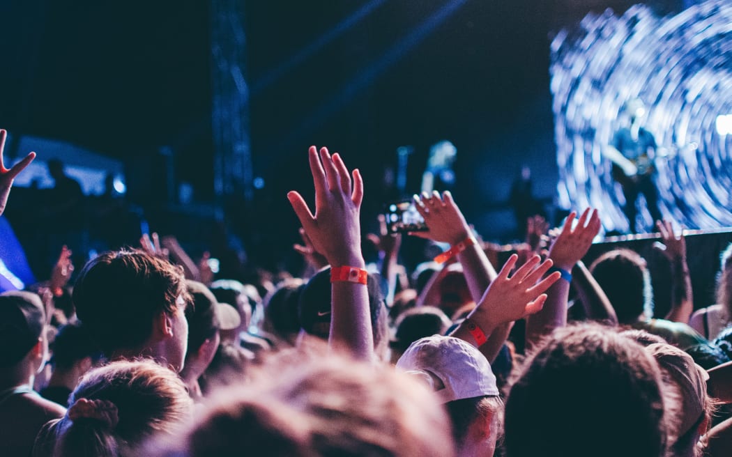 People waving their hands in the air at a music festival.