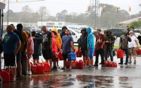 People wait in line to fill up their gas cans at a gas station that was damaged when Hurricane Florence hit Wilmington, North Carolina.