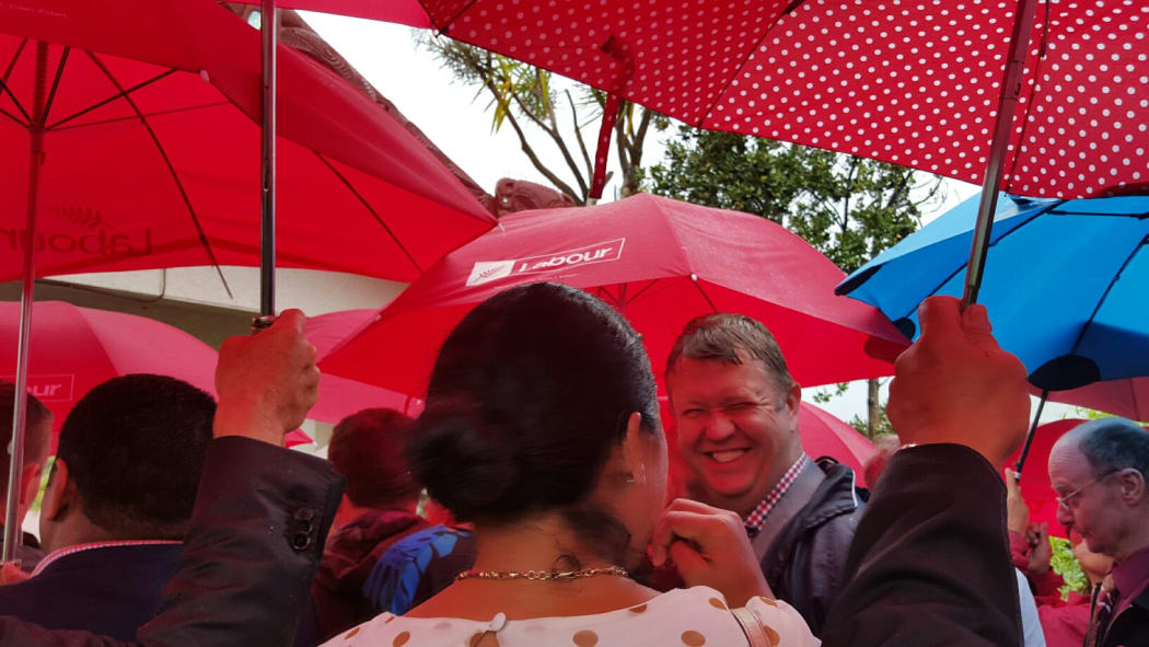 The Labour Party delegation lines up at the gate of the marae at Waitangi, amid a sea of red umbrellas.