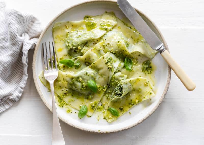 A bowl of triangular filled pasta garnished with basil leaves.