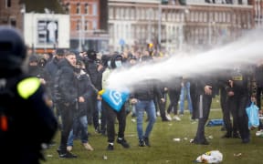 Demonstrators are sprayed by police water cannon at Amsterdam's Museumplein during a protest against the lockdown imposed to curb the spread of the Covid-19 pandemic and the outgoing government's policy, on January 21, 2021.