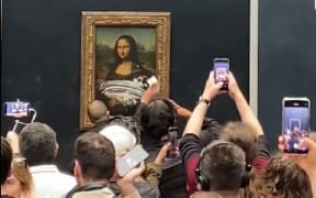 The glass which protects the Mona Lisa was left smeared with cream after a man disguised as an elderly woman in a wheelchair threw cake at it.