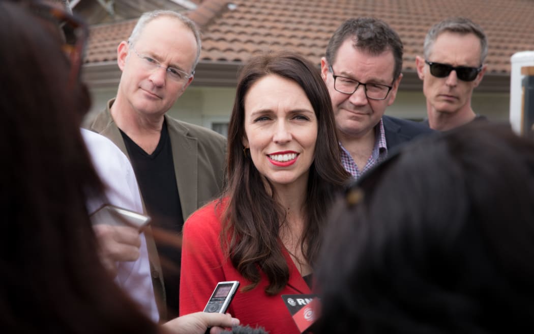 Jacinda Ardern (centre) speaking to media outside her home in Pt. Chevalier, Auckland. Phil Twyford (left) and Grant Robertson (right) stand with her.