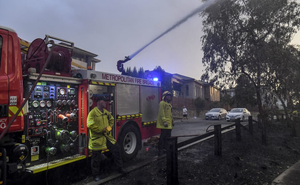 A firefighter dampens down a fire after a bushfire encroached on the outer suburbs of Melbourne on December 30, 2019.
