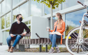 Students on university campus keeping social distance and wearing face masks due to coronavirus
