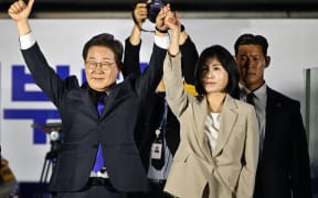 Lee Jae-myung (L) the presidential candidate for South Korea's Democratic Party, and his wife Kim Hye-gyeong (R) acknowledge supporters as they await the final results of the presidential election in Seoul on June 4, 2025. (Photo by ANTHONY WALLACE / AFP)