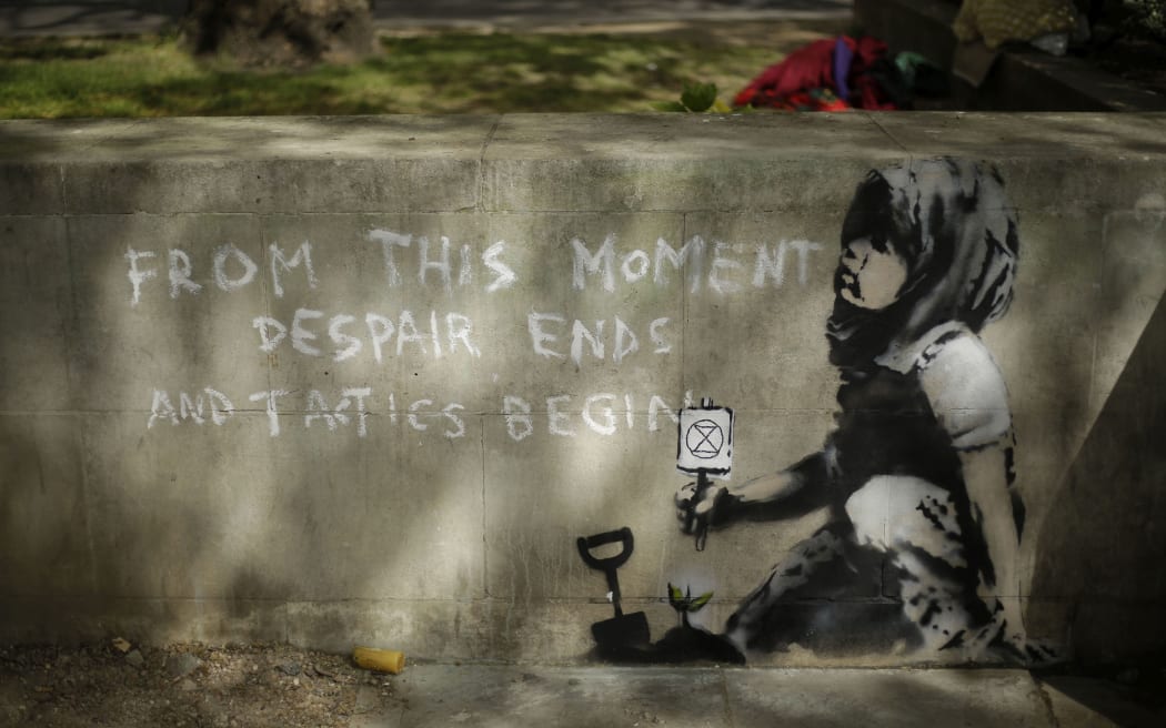 Dappled shade from a tree is cast over a new piece of street art that  is believed to be by street artist Banksy on a wall where Extinction Rebellion climate protesters had set up a camp in Marble Arch, London, Friday, April 26, 2019.