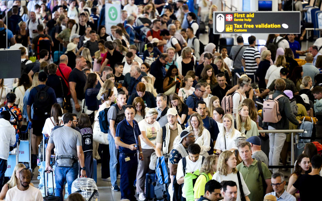 Long lines at the check-in desks in departure hall 1 at Schiphol. The airport is experiencing problems due to a major global computer outage and says the outage could impact flights to and from the airport.