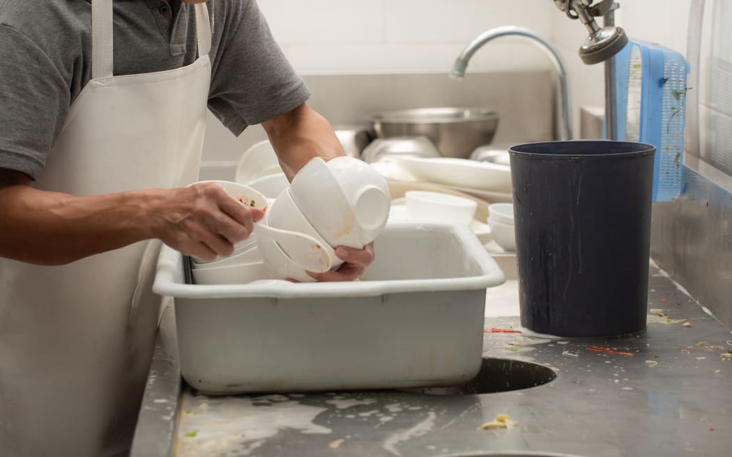 Man washing dish on sink at restaurant