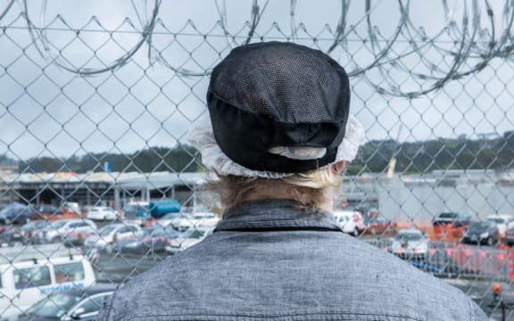 A prisoner looks out past a security fence at Paremoremo.