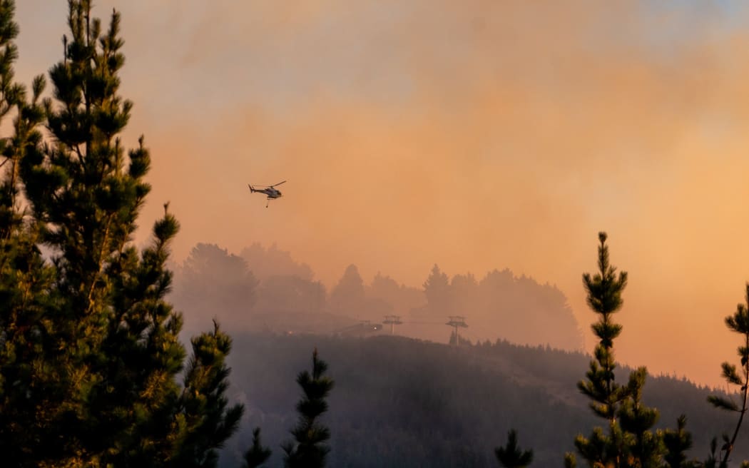 A helicopter can be seen attacking the vegetation fire at Christchurch's Port Hills on 14-15 February 2024.
