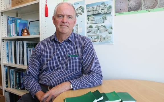 University of Auckland professor Paul Kilmartin sitting at his office, with green Collins diaries on the table and one in his shirt pocket.