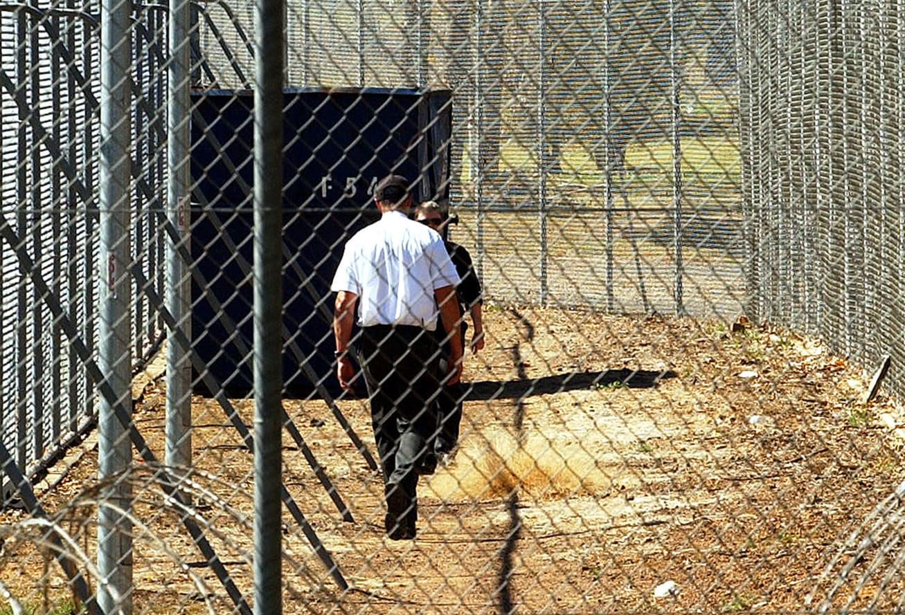 A Sept. 9, 2005 file photo of a guard walking inside the perimeter fence and razor wire that surrounds Villawood Detention Centre in Sydney.