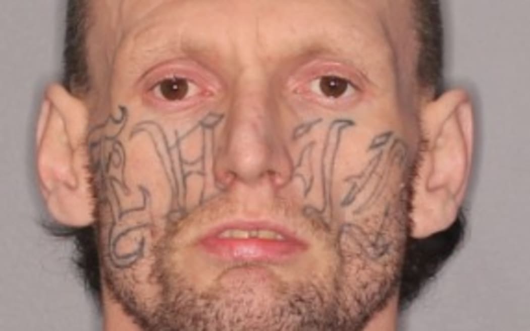 A man with a large tattoo across his entire face which says the word evil.