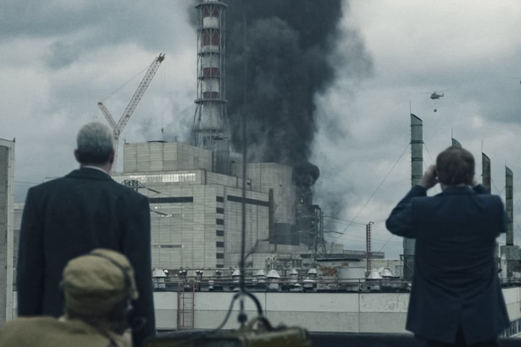 Comrades Legasov and Schcherbina watch as helicopters drop sand and boron on reactor four.