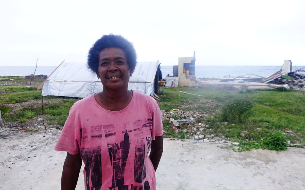 Rusila Delagi in front of her small makeshift house and her ruined home in the background Nasau village Koro Island Fiji