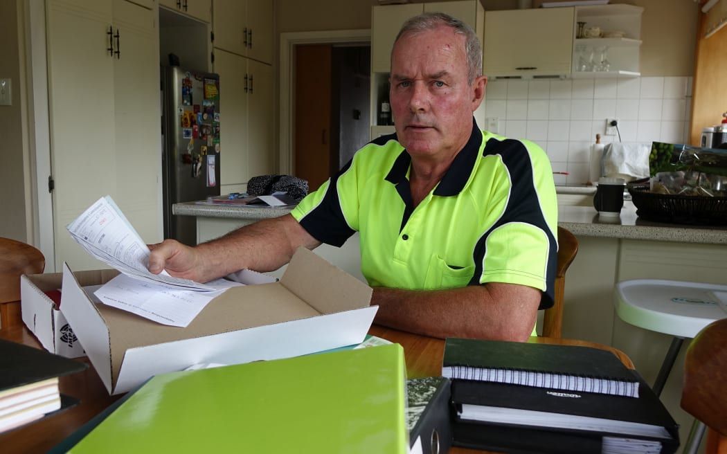 John Kerr sits at desk surrounded by files