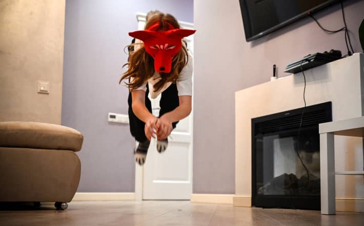 In this picture taken on October 18, 2024, Yana, a 12-year-old girl keen in quadrobics, wearing a fox mask practices in an apartment in Moscow. Quadrobics is a new fitness trend of imitating animal movements. (Photo by Alexander NEMENOV / AFP)