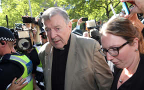 This file photo taken on February 27, 2019 shows Australian Cardinal George Pell (C) making his way to the court in Melbourne. - Cardinal George Pell will walk free from jail after winning a long-running battle to overturn his child sex abuse convictions in Australia's High Court on April 7, 2020.