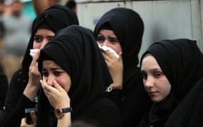 Iraqi women mourn at the site of the bombing in Baghdad's Karrada district during a symbolic funeral on July 10, 2016 for the victims of the attack. The Baghdad bombing claimed by the Islamic State group killed 292 people, according to a new toll issued on July 7, many of whom were trapped in blazing buildings and burned alive. A suicide bomber detonated an explosives-laden minibus early on July 3, ahead of the Eid al-Fitr holiday marking the end of the holy Muslim fasting month of Ramadan. (Photo by AHMAD AL-RUBAYE / AFP)