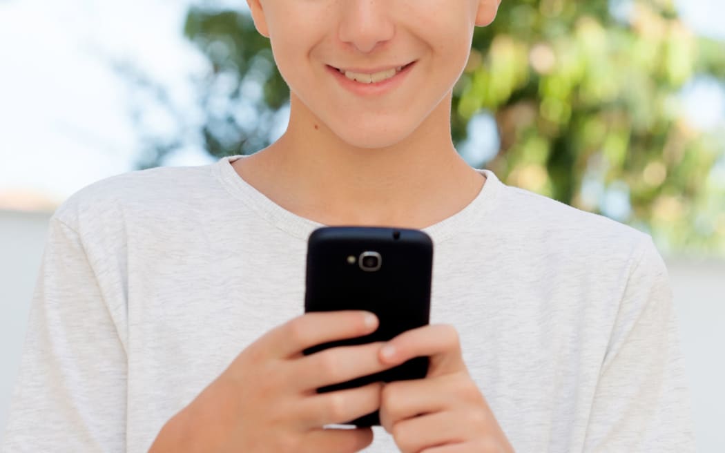 Funny teenage boy looking at the mobile