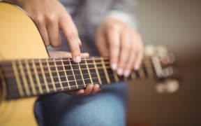 Teacher giving guitar lessons to pupil in a classroom