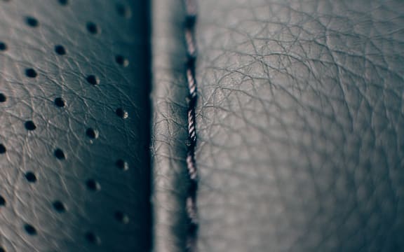 Close up of a detail of the stitches of a car seat in a black handmade leather upholstery.