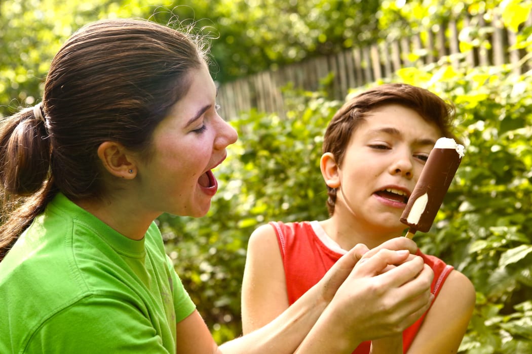 A photo of teen siblings, a boy and a girl quarreling over an ice-cream