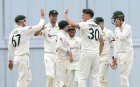 Pat Cummins (2R) and Nathan Lyon (L) of Australia celebrate the dismissal of Roston Chase of West Indies during the 2nd day of the 1st Test match between West Indies and Australia at Kensington Oval, Bridgetown, Barbados, on June 26, 2025. (Photo by Randy Brooks / AFP)