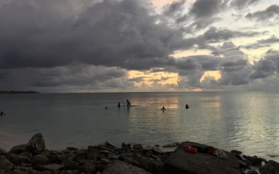 Funafuti lagoon, Tuvalu at sunset with a few  people in the water