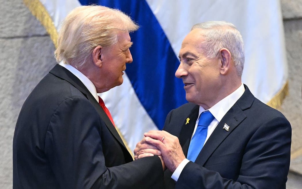 US President Donald Trump (L) holds hands and speaks with Israeli Prime Minister Benjamin Netanyahu at the Israeli parliament, the Knesset, in Jerusalem on October 13, 2025. Hamas handed over the 20 surviving Israeli hostages on October 13 under a ceasefire agreement, as the US President and other world leaders geared up for a summit on Gaza. The releases are part of a ceasefire agreement brokered by the US President, with Israel due in return to free nearly 2,000 detainees held in its jails in exchange.