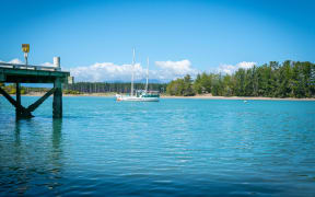 Wharf at Mapua with slopp moored in channel of Waimea Estuary on Tasman Bay in South Island New Zealand.