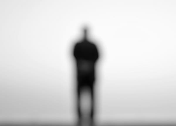 A fuzzy image of a lone figure in black and white.