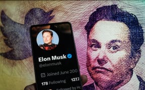 Elon Musk Twitter account seen on Mobile with Elon Musk in the background seen in this photo illustration.