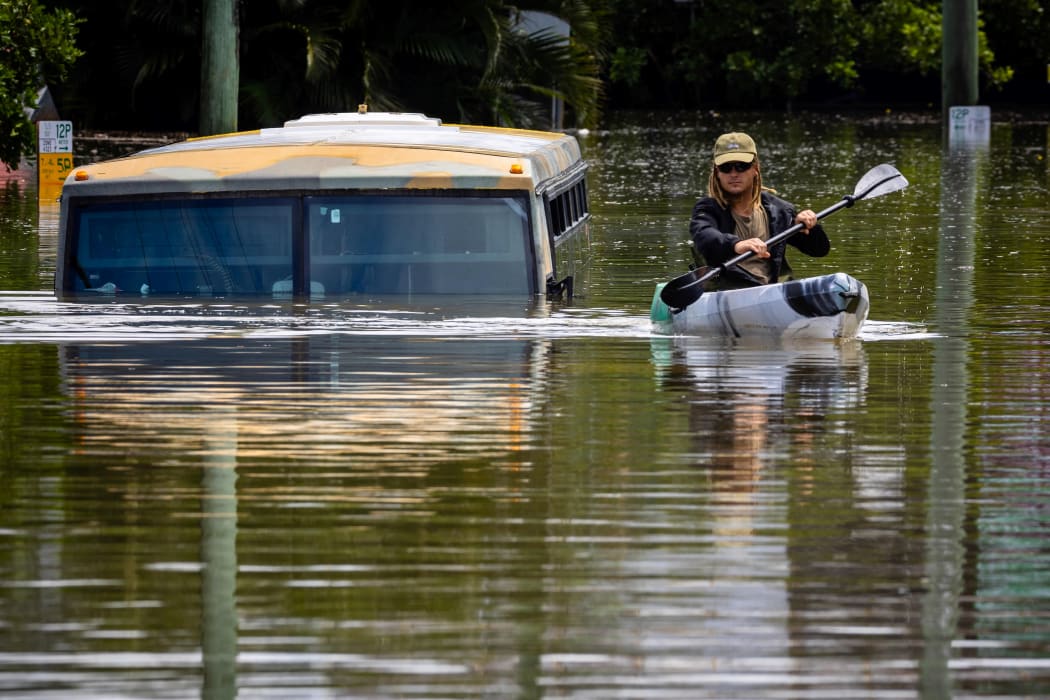 A man paddles his kayak next to a submerged bus on a flooded street in the town of Milton in suburban Brisbane on February 28, 2022.