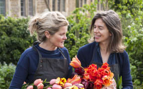 THE LAND GARDENERS, WARDINGTON MANOR, OXFORDSHIRE: BRIDGET ELWORTHY AND HENRIETTA COURTAULD HOLDING CUT TULIPS FOR FLOWER ARRANGING. CUT FLOWER, CUTTING GARDEN, WALLED GARDEN