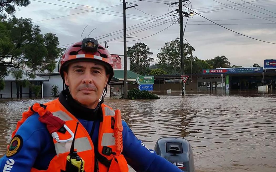 A NSW State Emergency Service worker steering his boat through the flooded streets of the northern NSW town of Lismore following Tropical Cyclone Debbie.