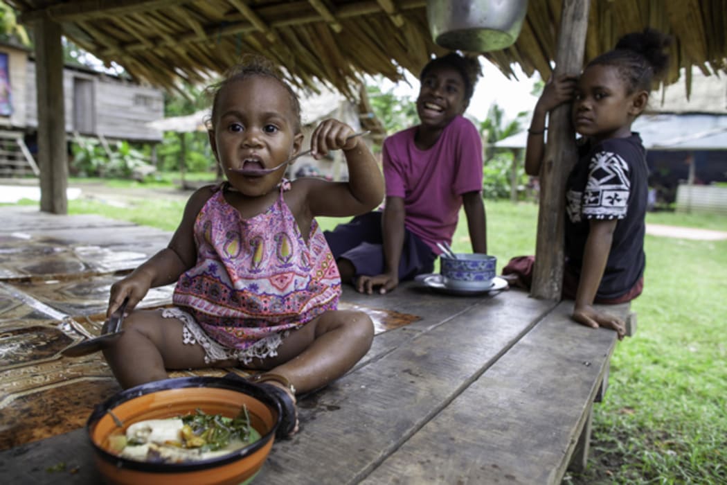 A girl eats vegetable broth in Guadalcanal, Solomon Islands.