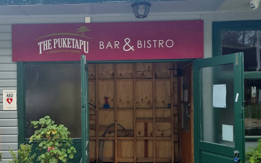 The door to The Puketapu pub showing ply wood lining inside after being flood damaged.