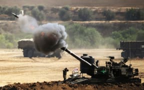 An Israeli artillery gun fires a shell towards targets from their position near Israel's border with the Gaza Strip.