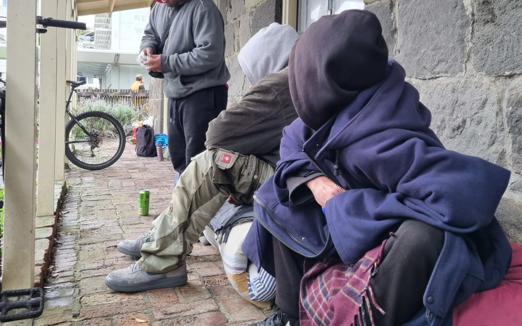 A group of homeless people sheltering under the verandah of the earthquake-prone Richmond Cottage in New Plymouth.