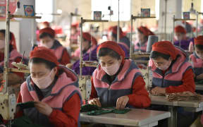 Workers of Songyo Knitwear Factory in Pyongyang produce masks for protection against the coronavirus.