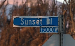The Sunset Boulevard street sign is seen among rubble of homes destroyed in the Palisades Fire, in the Pacific Palisades neighborhood of Los Angeles, California, on January 18, 2025. Tens of thousands of people ordered to flee their homes as wildfires tore through Los Angeles were told on January 16 they would not be allowed back for at least a week, with fears over electrocution, landslides and exposure to toxic materials. 
Frustration is mounting among evacuees, who are angry over rules that restrict them from returning to their homes, even if the structures survived the deadly blazes. (Photo by Robyn Beck / AFP)