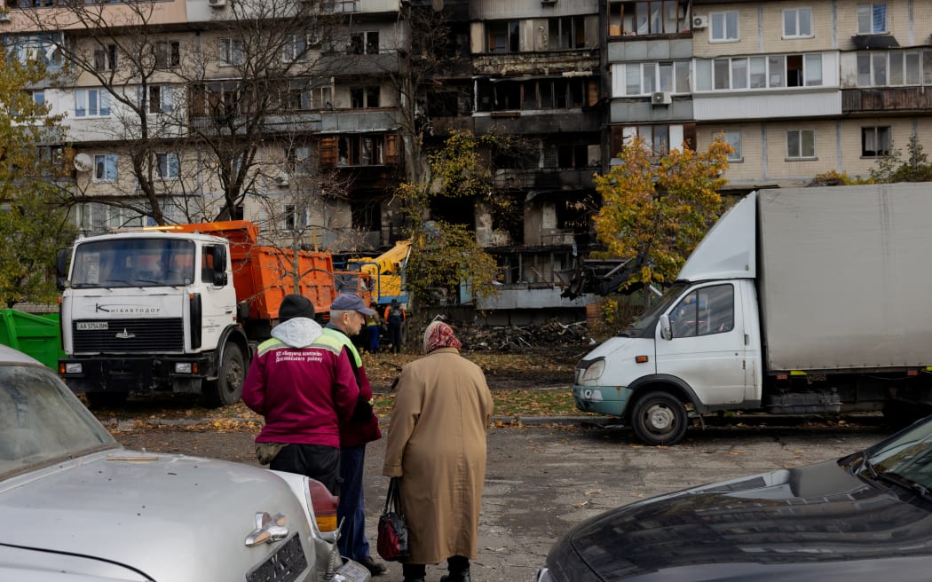 Local residents look at a damaged residential building following a drone attack in Kyiv, on 26 October, 2025, amid the Russian invasion of Ukraine.